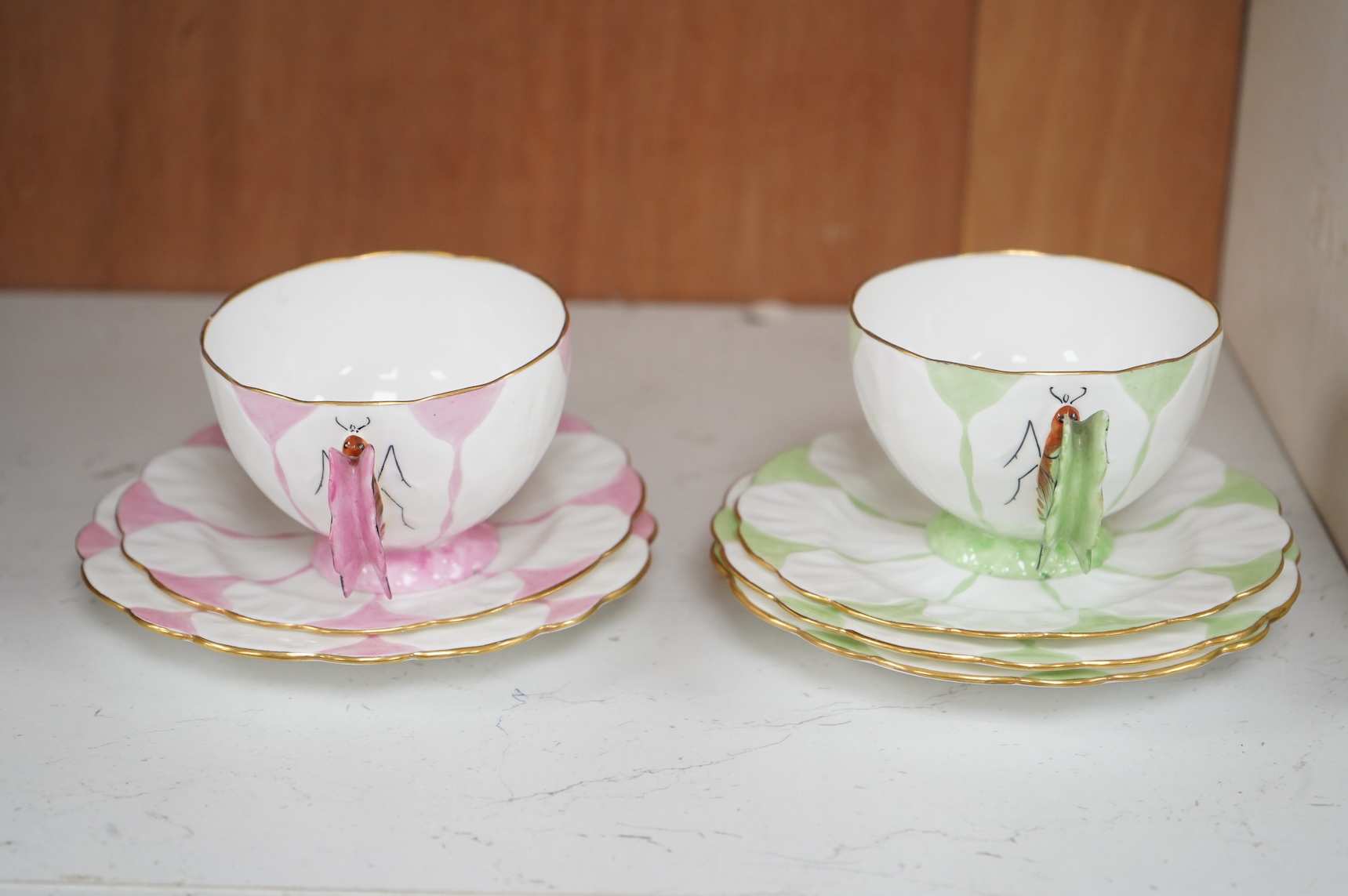 Two Aynsley trios with butterfly handles and one extra saucer, numbered 785788